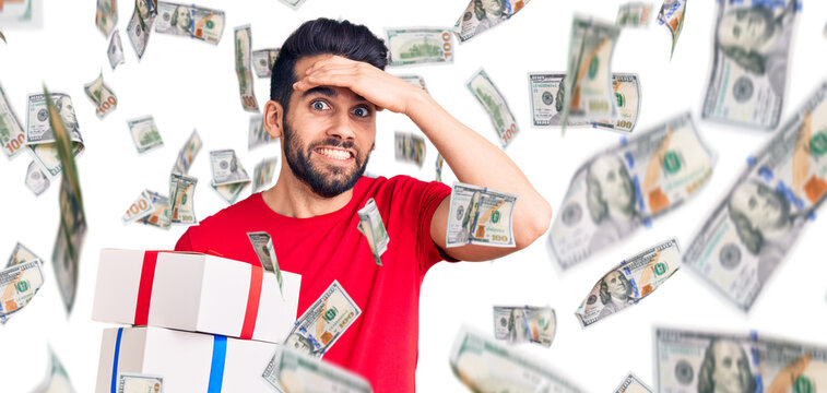 Young handsome man with beard holding gift stressed and frustrated with hand on head, surprised and angry face