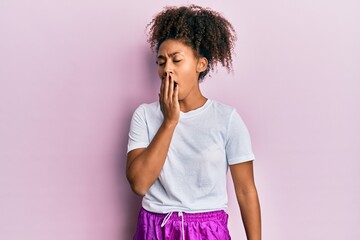 Beautiful african american woman with afro hair wearing sportswear bored yawning tired covering mouth with hand. restless and sleepiness.