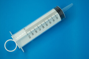 plastic large syringe 100 ml, on a blue background.