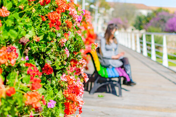 Joven mujer con mascarilla sentada junto a un jardín de flores en Valencia (España), en un día de primavera. 