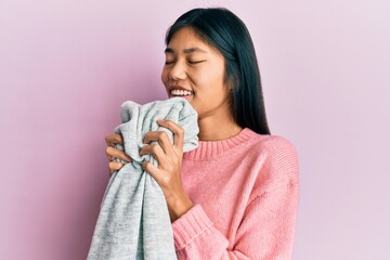 Young asian woman smelling laundry scent from clean sweater