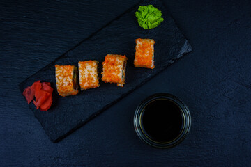 Sushi roll philadelphia with salmon, rice, cheese, cucumber, avocado and caviar on a slate board. Japanese food. Top view