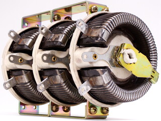 Closeup on some electrical components consisting of heavy, wound wiring on a ceramic base, with...