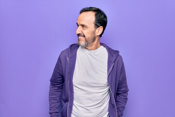 Middle age handsome sporty man wearing casual purple sweatshirt over isolated background looking to side, relax profile pose with natural face and confident smile.