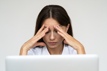 Woman feeling headache, weakness, tired, exhausted from work on laptop at home office over grey...