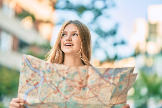 Beautiful caucasian tourist teenager smiling happy holding map at the city.