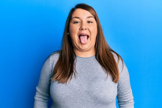 Beautiful brunette plus size woman wearing casual clothes sticking tongue out happy with funny expression. emotion concept.
