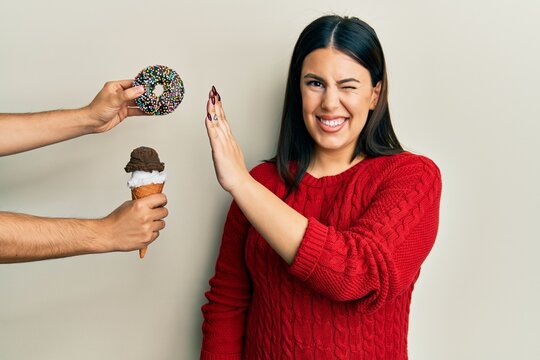 Beautiful Brunette Woman Saying No To Sweets On A Healthy Diet Winking Looking At The Camera With Sexy Expression, Cheerful And Happy Face.