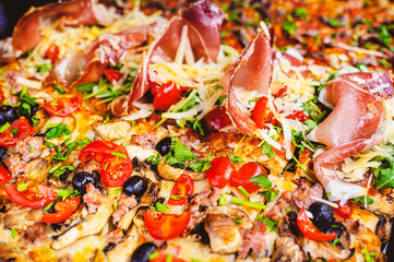 Close up of different gourmet pizza slices with multiple ingredients. Cherry tomatoes, black...