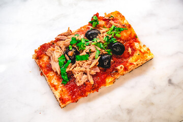 Pizza slice with tomato sauce, tuna fish, black olives and parsley_Angle
