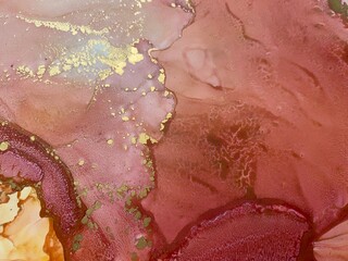 Abstract art with gold — pink-orange-yellow background with beautiful smudges and stains made with alcohol ink and golden pigment. Fragment of art with pink texture resembles watercolor or aquarelle.
