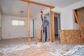 Carpenter measuring a demolished room