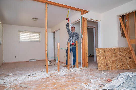 Carpenter Measuring A Demolished Room