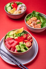 Set of fresh poke bowl with salmon, avocado, chukka, basil,shrimp and smoked fish on red background with place for text
