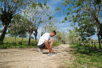 Runner sportsman tying shoelaces in nature.