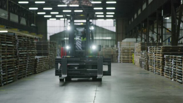 Forklift truck drives backwards through stacked pallets