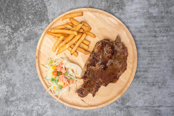 Top view Grilled pork steak with vegetable salad and french fries on wooden table.