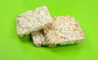 Puffed rice cakes on green background. Stack of puffed whole grain crispbread on green background.