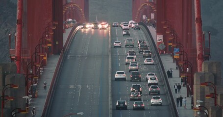 San Francisco, October 2020. Close up view on evening traffic on Gold Gate Bridge at pink sunset. The police car is closing lane in upcoming direction. Slow motion transportation on famous landmark