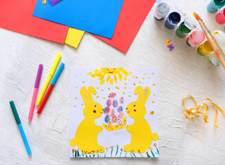 Child making card with Easter bunnies  from colorful paper. Applique. Handmade. Project of children's creativity, handicrafts, crafts for kids.
