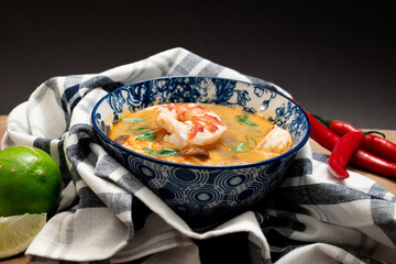 Tom Yum soup in a decorative bowl on a wooden table