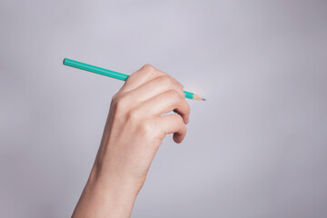 Hand holding a green pencil on white background