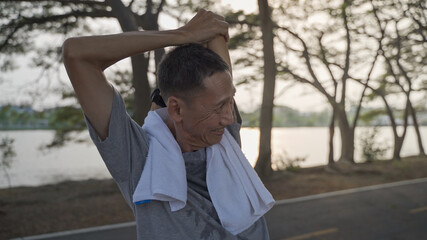 senior man exercise and stretching at park in evening