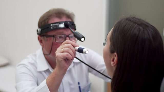 Otolaryngologist is examining woman's throat in clinic