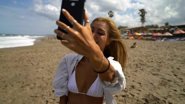 Young happy woman taking selfie photo with cellphone on beach