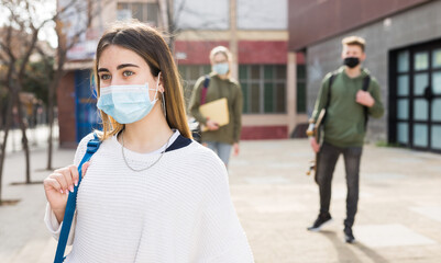 Fototapeta na wymiar Portrait of girl teen student in protective face mask on her way to college in sunny spring day