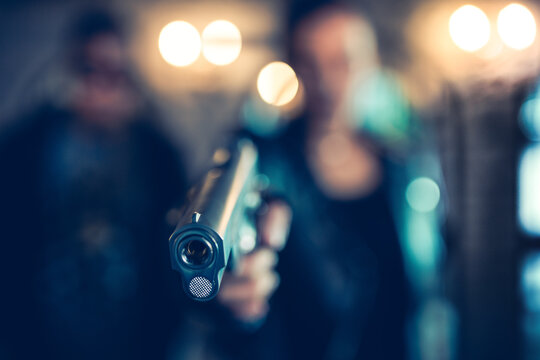 Woman Pointing A Gun To The Front With One Hand In The Dark Background. Soft Focus.