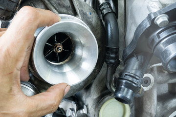 Turbo charger on car engine with hand of mechanic while inspecting the turbine blades of Turbo charger with copy space on background
