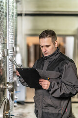 Side view of adult man winemaker at winery checking quality while standing between the silos controlling alcohol drink fermentation process - real people traditional and industry wine making concept © Miljan Živković