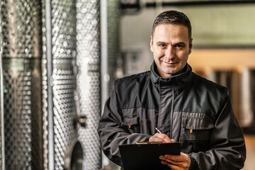 Side view of adult man winemaker at winery checking quality while standing between the silos controlling alcohol drink fermentation process - real people traditional and industry wine making concept © Miljan Živković