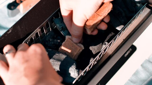 Placing firestarters in a grill ready to fire up the barbeque
