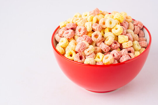 Cereal Flakes In Red Bowl With Copy Space,Breakfast Concept.Food With Delicious Fruity Taste And Fruity Colours.It's Made With Maize,wheat,and Barley.topview And Copy Space.white Background.