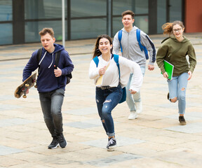 Cheerful teenagers are jogging together on the street and having fun