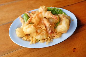 Deep fried peeled shrimp with flour in plate on wood table. Crispy seafood.