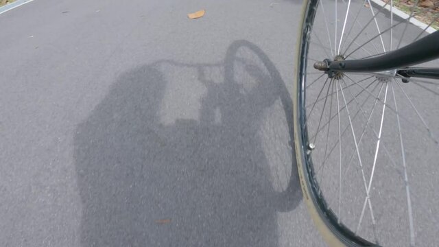 Wheel cam POV on a vintage bicycle, shadow of rider on floor, on a rural bike path.