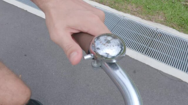 POV of a caucasian man ringing a bell on a vintage bicycle, on a rural bike path.