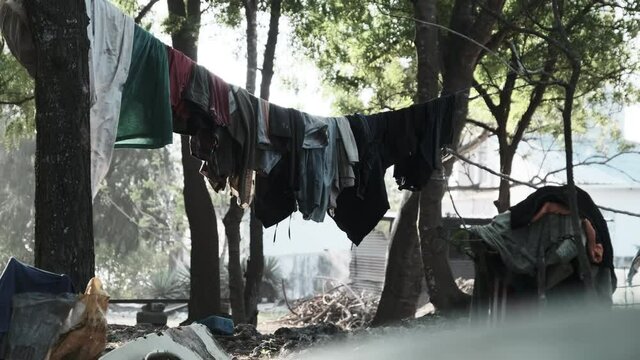 Clothes are dried on a clothesline in a poor African village. Various Colourful clothes, T-shirts, pants hanging out to dry on a rope between the palm trees. Lot of Washings are drying outside. Africa