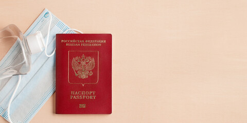 Safe travel during coronavirus pandemic concept. Protective medical mask, sanitizer and Russian passport on the table, copyspace, flatlay