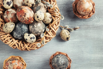 Easter composition - several marble eggs painted with natural dyes in a wicker nest and baskets, top veiw