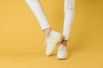 Womens legs white pants sneakers fashion clothes luxury street style yellow background