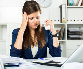 Tired young businesswoman working with documents in office. High quality photo