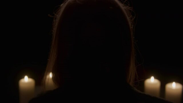 View Behind Mysterious Woman Takes Off Black Robe Hood at Candlelight Altar
