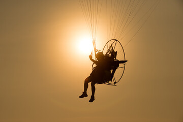 Silhouette paraglider under play paramotor extreme sport, transportation fly on sky with sunlight...