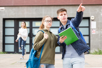 Fototapeta premium Positive teenage friends discuss past lessons on the street near college building
