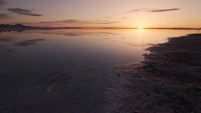 Panning over the shoreline on the Bonneville Salt Flats reflecting the sunrise at the Great Salt Lake.