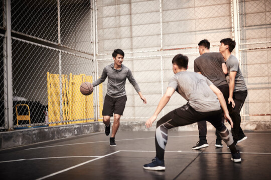 young asian men playing basketball outdoors